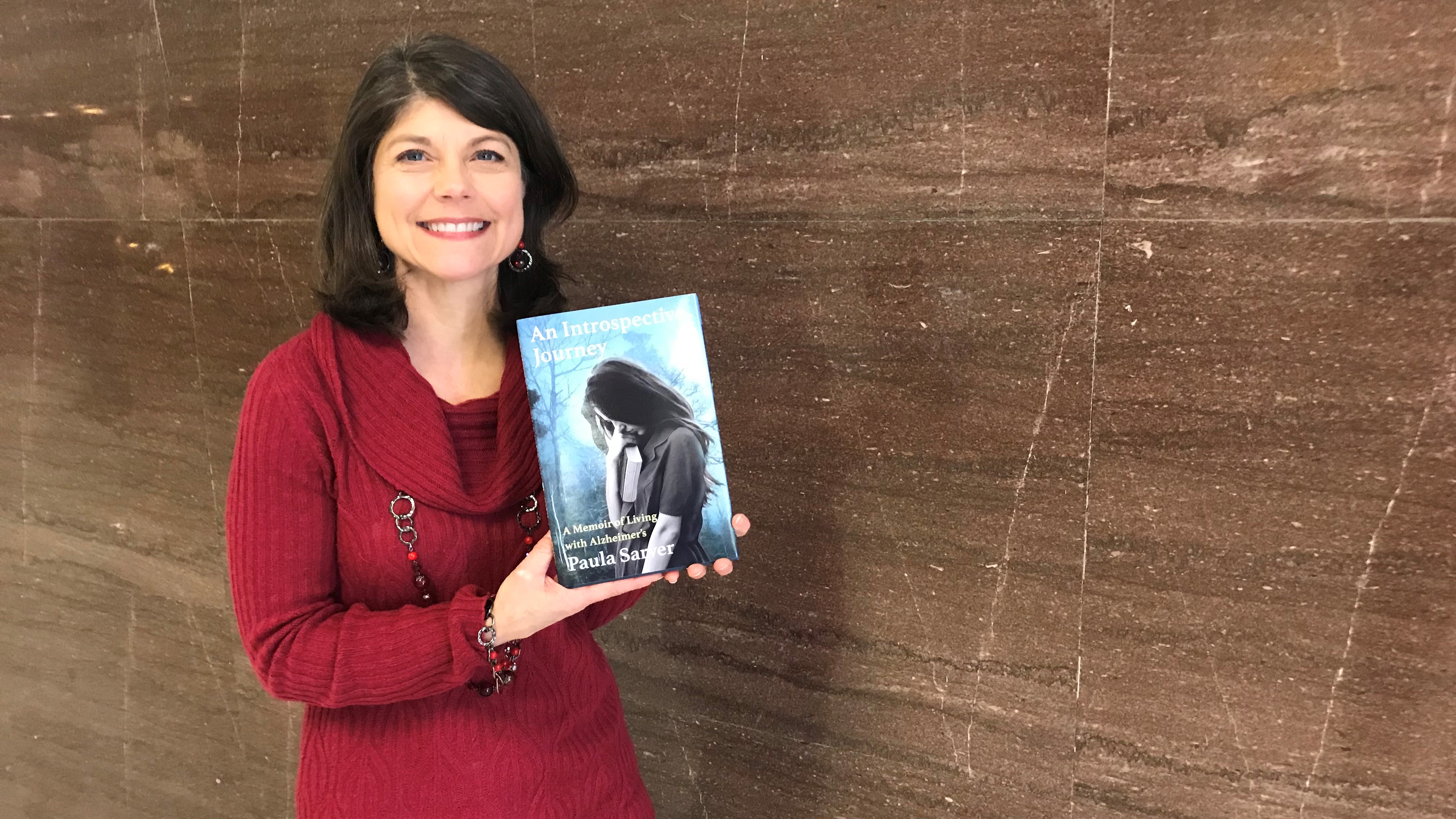 Paula Sarver displays her new book, An Introspective Journey, a memoir about her mother's struggle with Alzheimer's. 